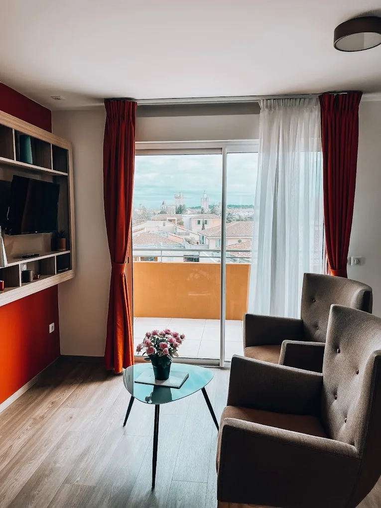 Living area of an apartment in Uzès opening through a glazed door onto the balcony and the tiled rooftops of the old town